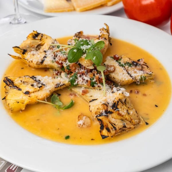 Grilled artichoke hearts in a creamy orange sauce, topped with parmesan, bacon, and basil.